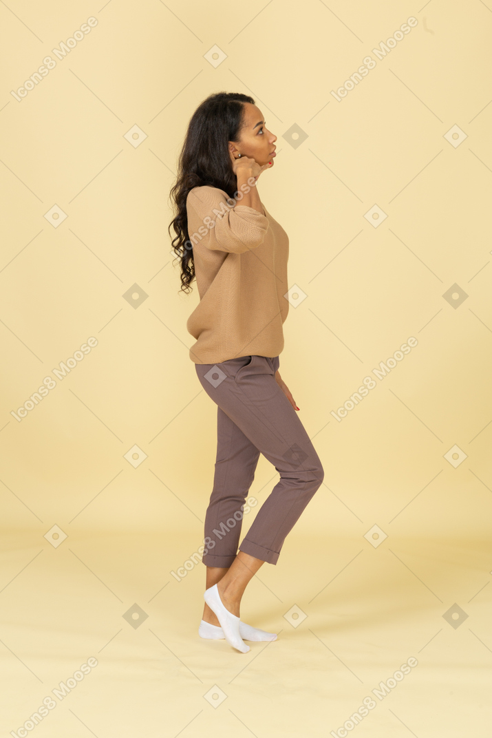 Side view of a dark-skinned young female making a phone call gesture