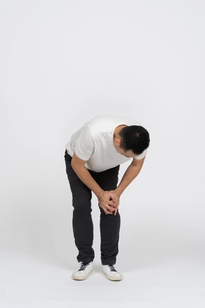 Front view of a man bending down and touching hurting knee