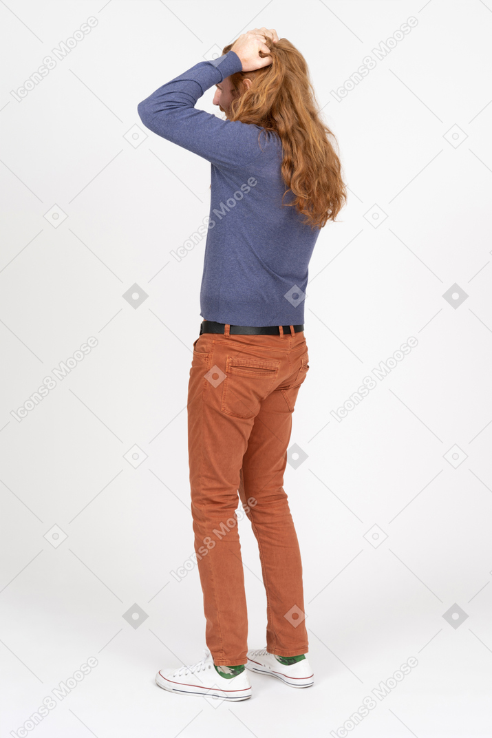 頭に手を置いて立っているカジュアルな服装の若い男