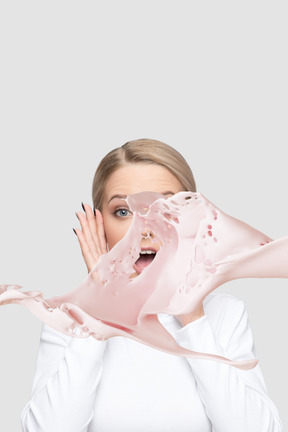 A woman getting splashed in the face with pink liquid