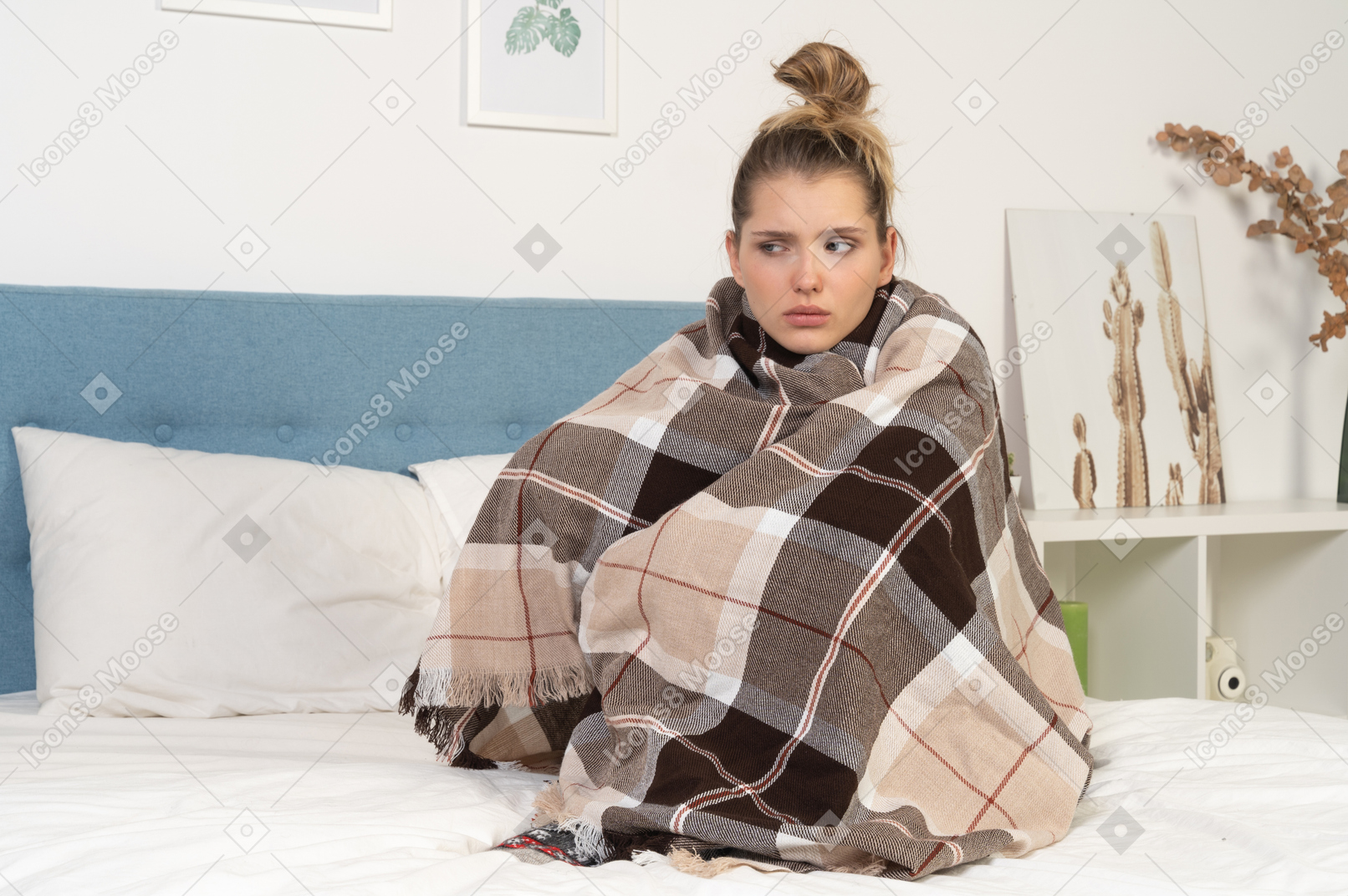 Front view of an ill young lady wrapped in checked blanket in bed