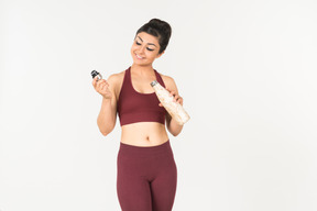 Jeune femme indienne sportswear tenant une bouteille de sport