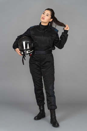 A sel-confidnt young woman holding a helmet and touching her hair