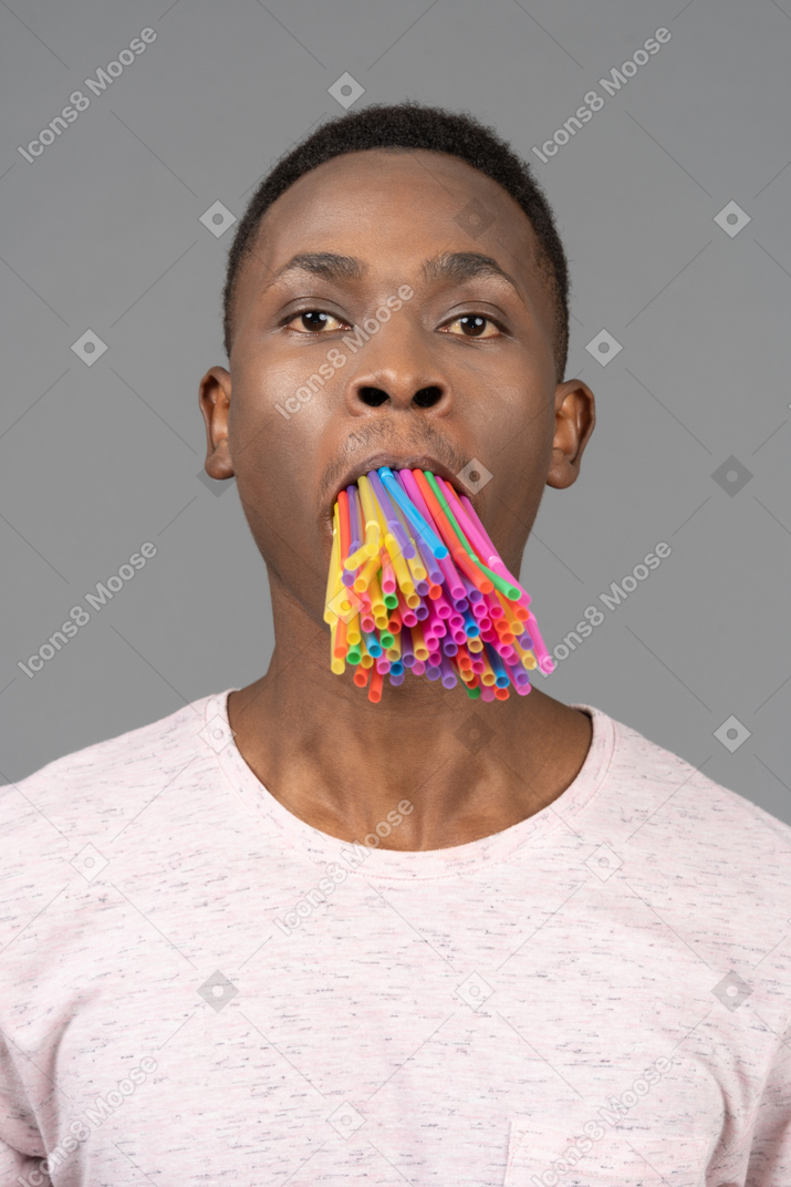 Junger mann mit einem bündel strohhalme im mund