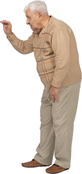 Side view of an old man in casual clothes waving