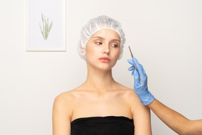 Young attractive woman and surgeon's hand with scalpel