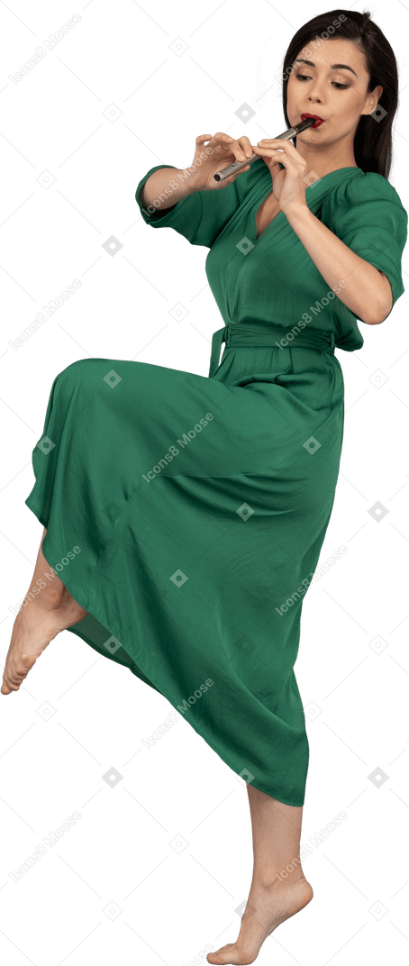 Vista lateral de uma jovem dançando com vestido verde tocando flauta