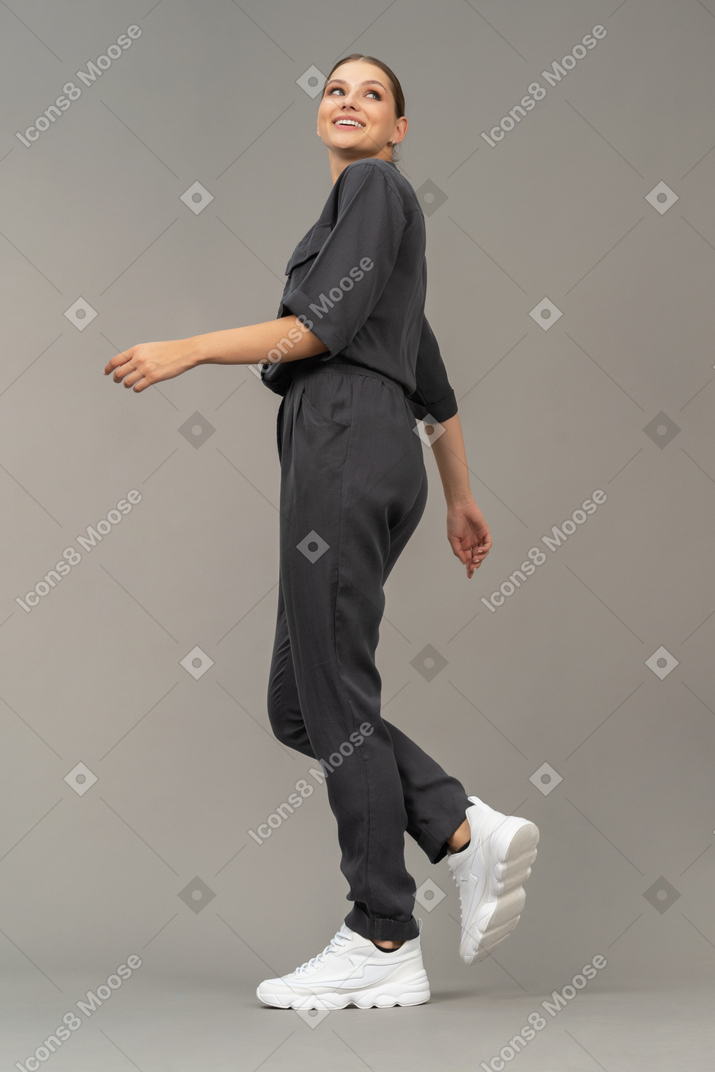 Side view of a smiling walking young woman in a jumpsuit