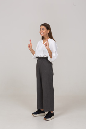Vista de tres cuartos de una joven en ropa de oficina cruzando los dedos