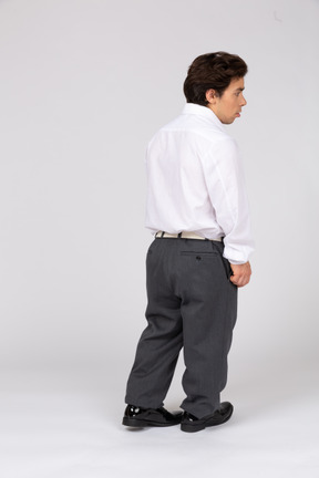 Молодой человек в деловой повседневной одежде стоит спиной к камере