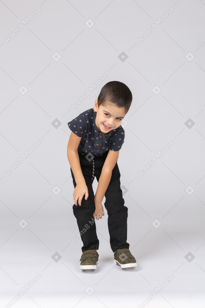 一个可爱的男孩弯腰触摸膝盖的前视图