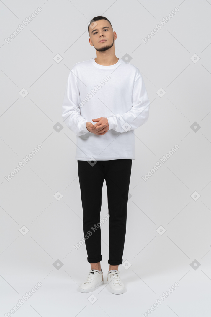Молодой человек в повседневной одежде стоит с руками по бокам
