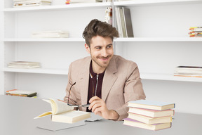 A man sitting at a table with a stack of books