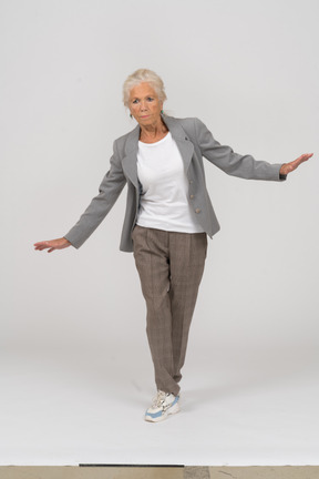 一位身着西装的老妇人张开双臂站立的前视图