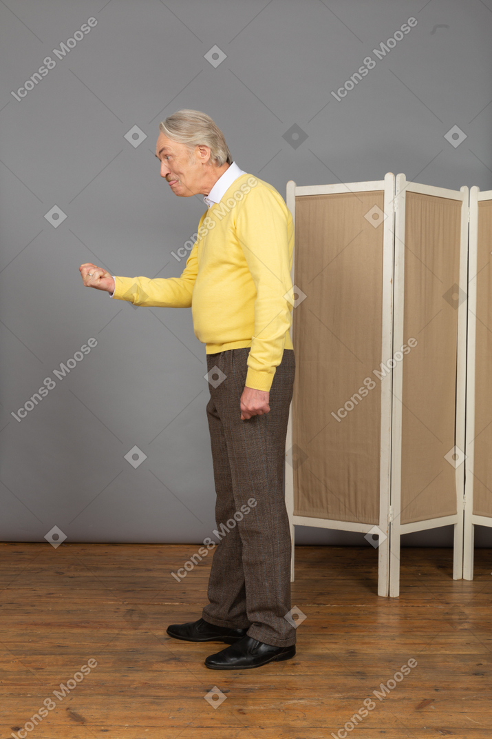Vista lateral de um homem velho com raiva cerrando os punhos