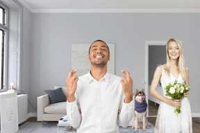 Young man crossing his fingers and young woman holding bouquet in living room