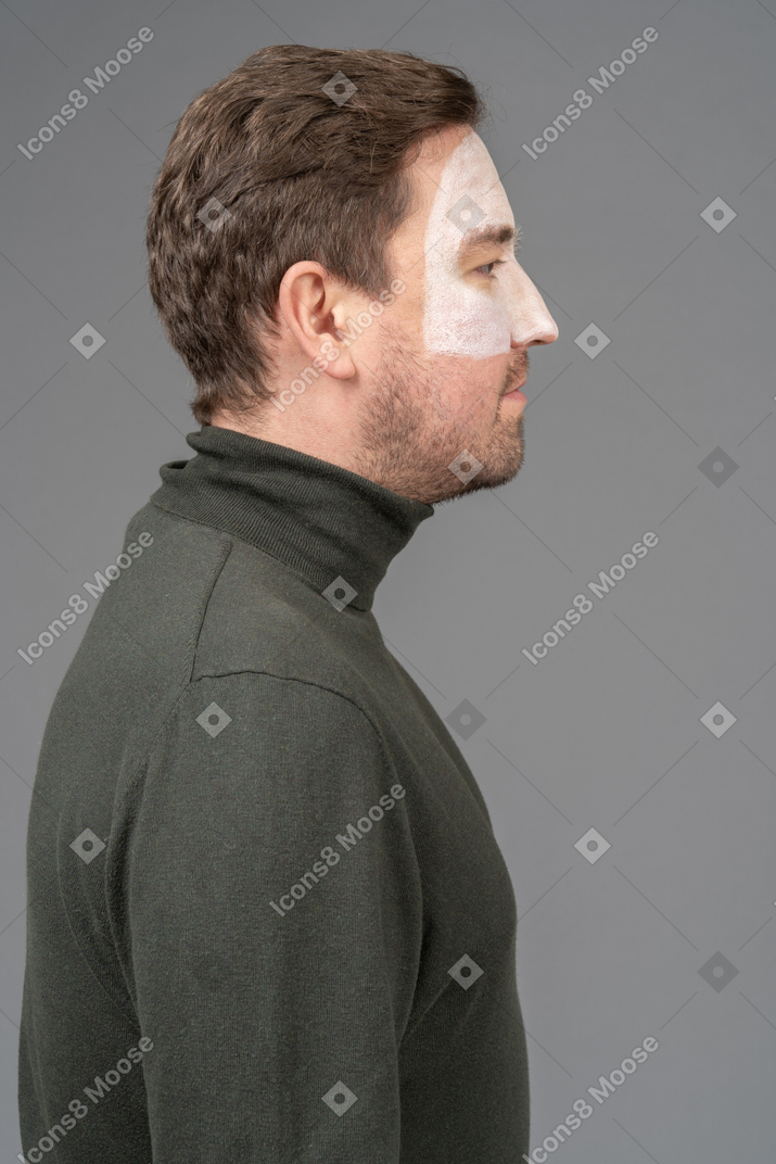 Side view of a male football fan with a white face art