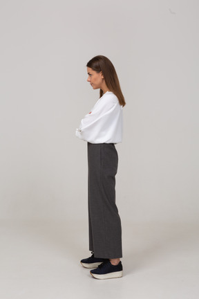 Side view of a serious young lady in office clothing crossing arms and looking aside
