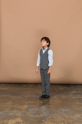 一个穿着灰色西装的男孩站着不动的前视图