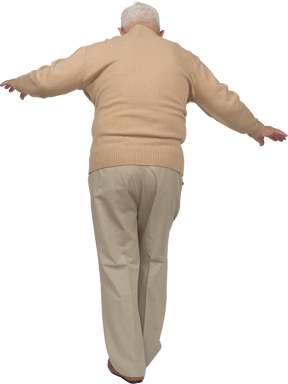 Вид сзади на старика в повседневной одежде, идущего с распростертыми руками