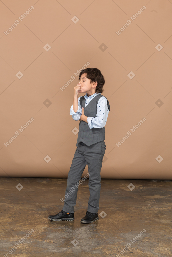 Side view of a boy in grey suit pinching nose
