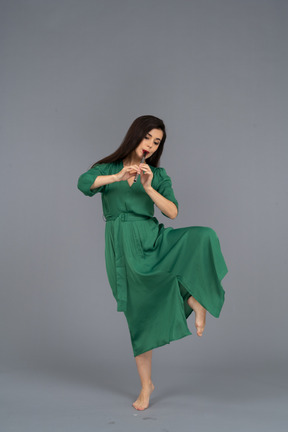 Vista frontal de una jovencita bailando en vestido verde tocando la flauta