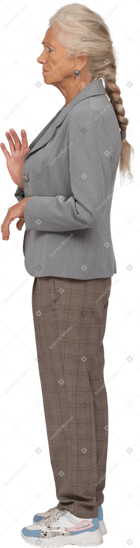 Sad old lady in suit standing in profile and waving