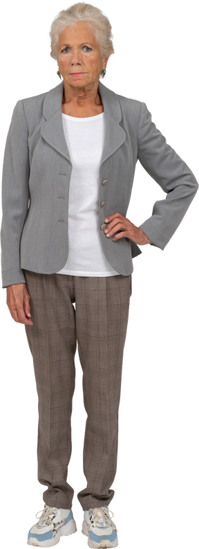 Front view of an old lady in suit posing with hand on hip
