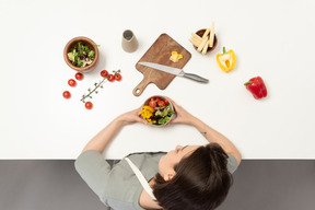 A young woman holding a bowl of vegetables