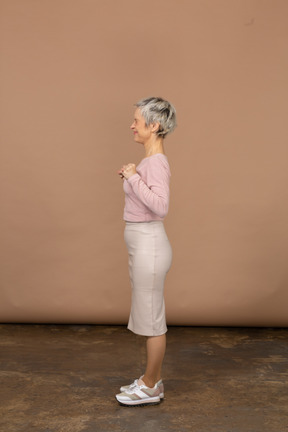 Vista lateral de uma mulher feliz em roupas casuais em pé com os punhos cerrados