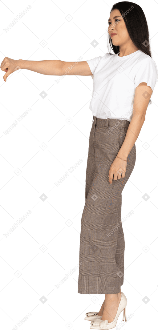 Vista di tre quarti di una giovane donna in calzoni e maglietta che mostra il pollice verso il basso