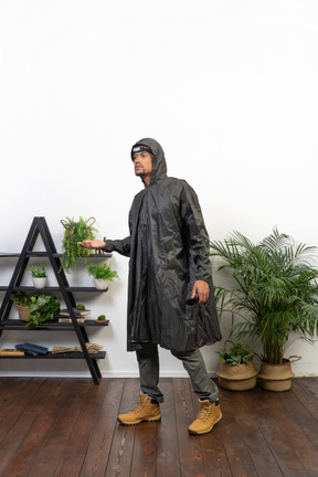 Man in raincoat catching raindrops onto palm
