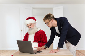 Der weihnachtsmann schläft, während der mann mit dem laptop arbeitet