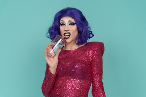 Drag queen in pink sequin dress showing teeth while having a sip