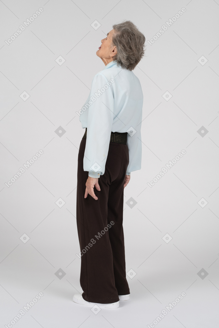 Three-quarter back view of an old woman looking up with a grimace