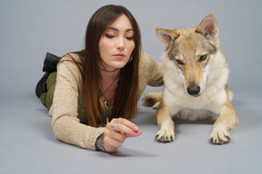 A figura intera di un maestro femmina sdraiato dal suo cane e guardando la fotocamera