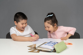 Jungen und mädchen lachen, während sie hausaufgaben machen