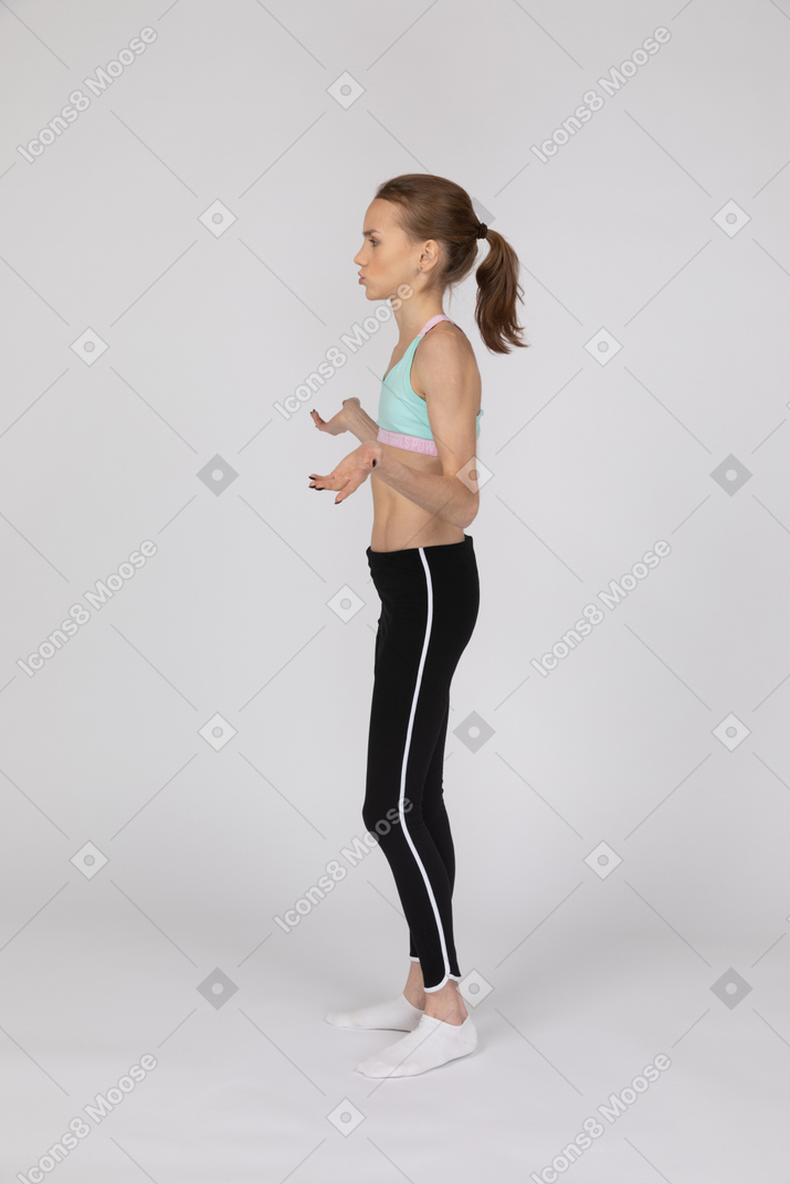 Vista laterale di una ragazza adolescente in abiti sportivi alzando la mano e sostenendo