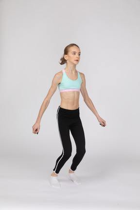 Side view of a teen girl in sportswear squatting and putting hands on hips