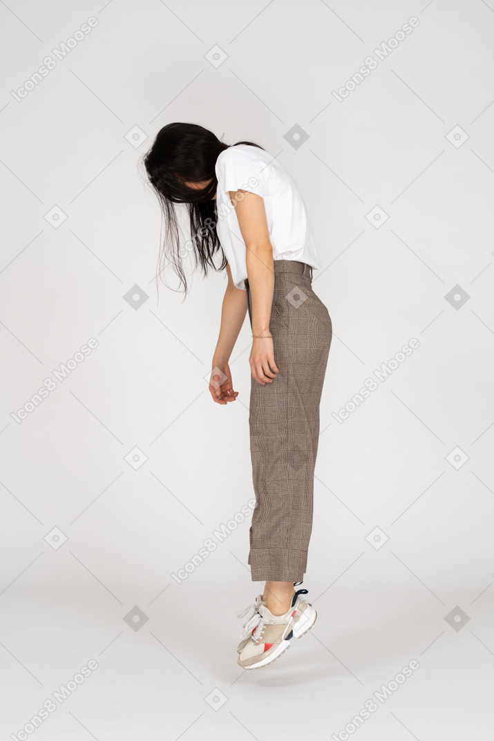 跳跃的年轻女士，在马裤和t恤往下看的侧视图