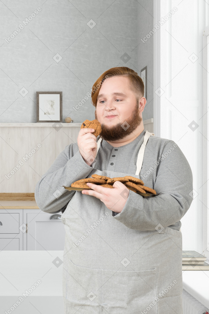 A man in an apron holding a plate of food