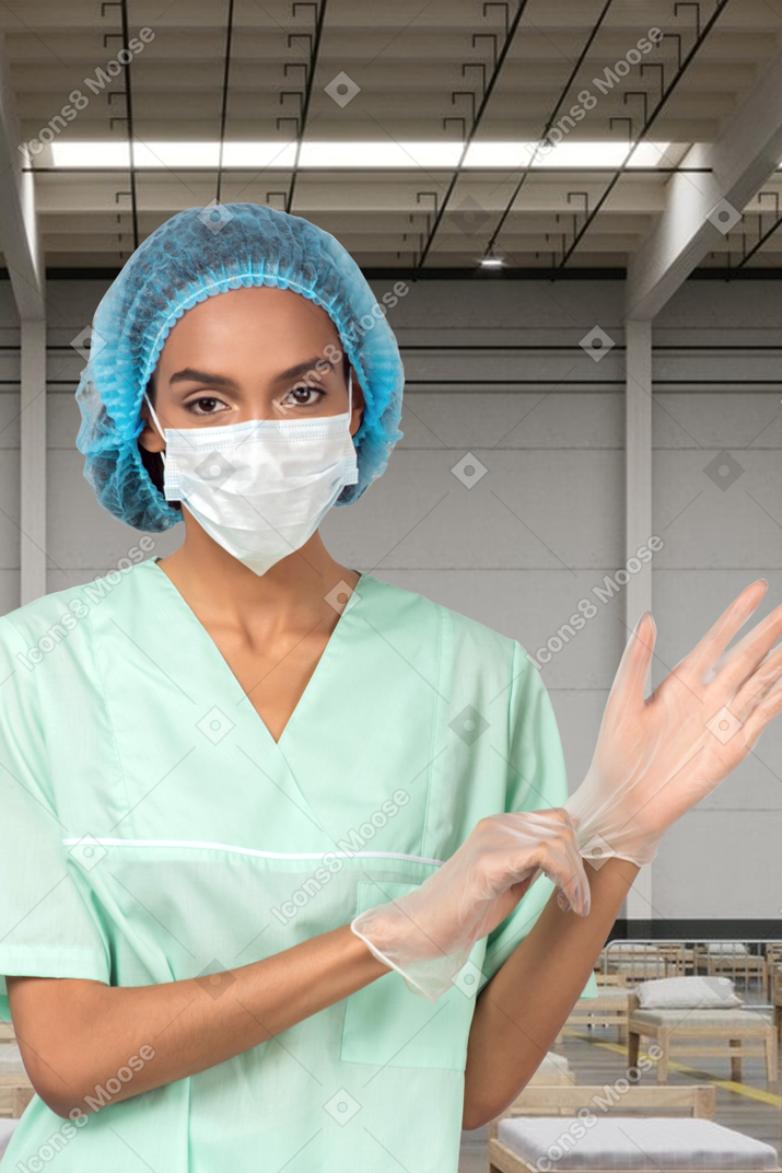 Medical worker in face mask putting on gloves