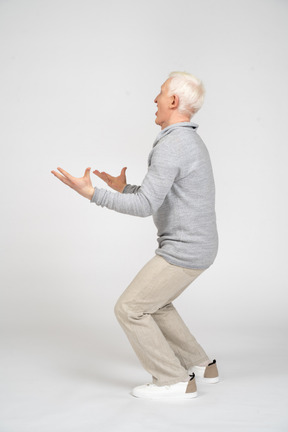 Side view of a man with bent knees and holding up his hands