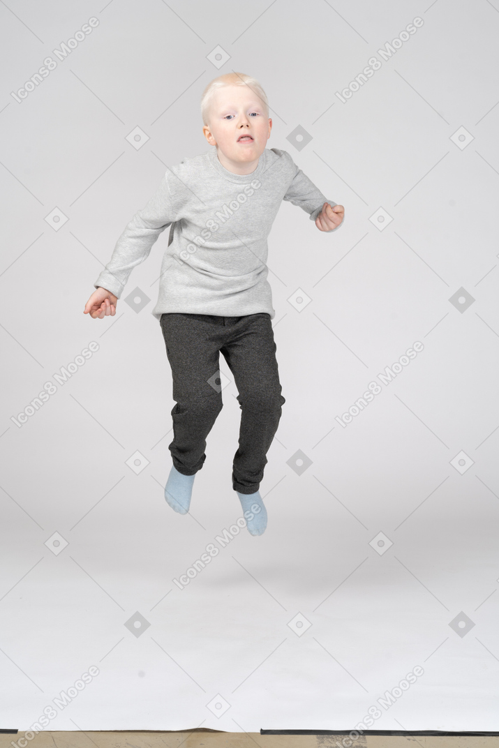 Vista frontal de um menino pulando alto