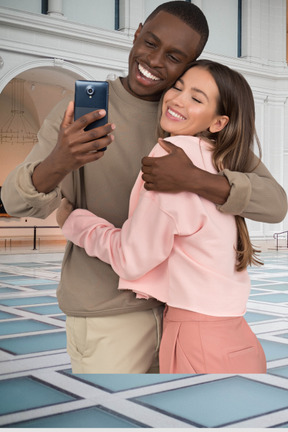 A man and woman taking a selfie with a cell phone