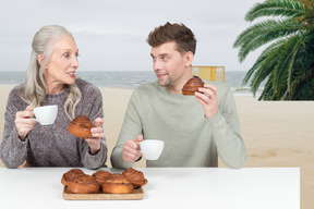 A man and woman sitting at a table and eating pastries