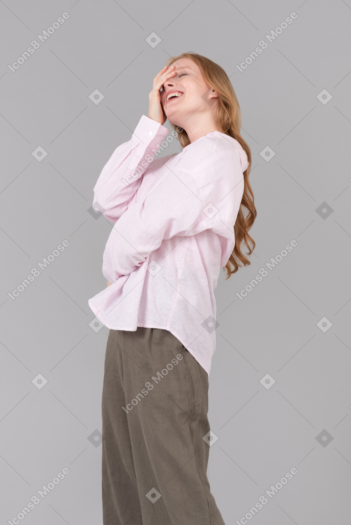 Laughing young woman touching her face