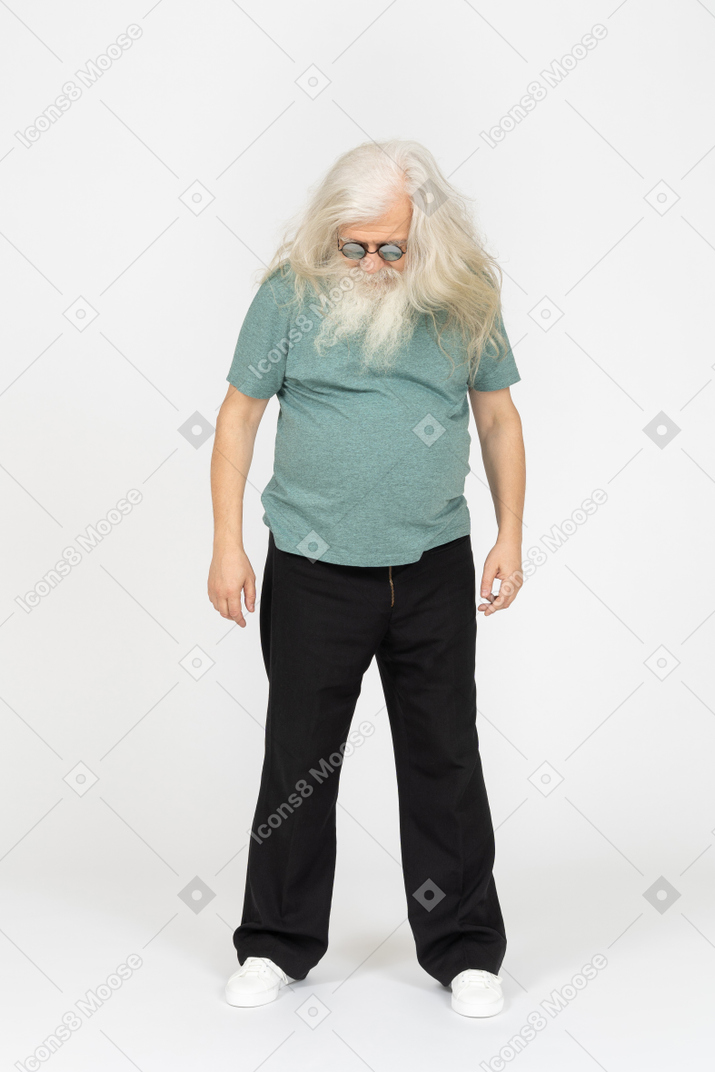 Vista frontal del anciano con gafas de sol de pie y mirando hacia abajo