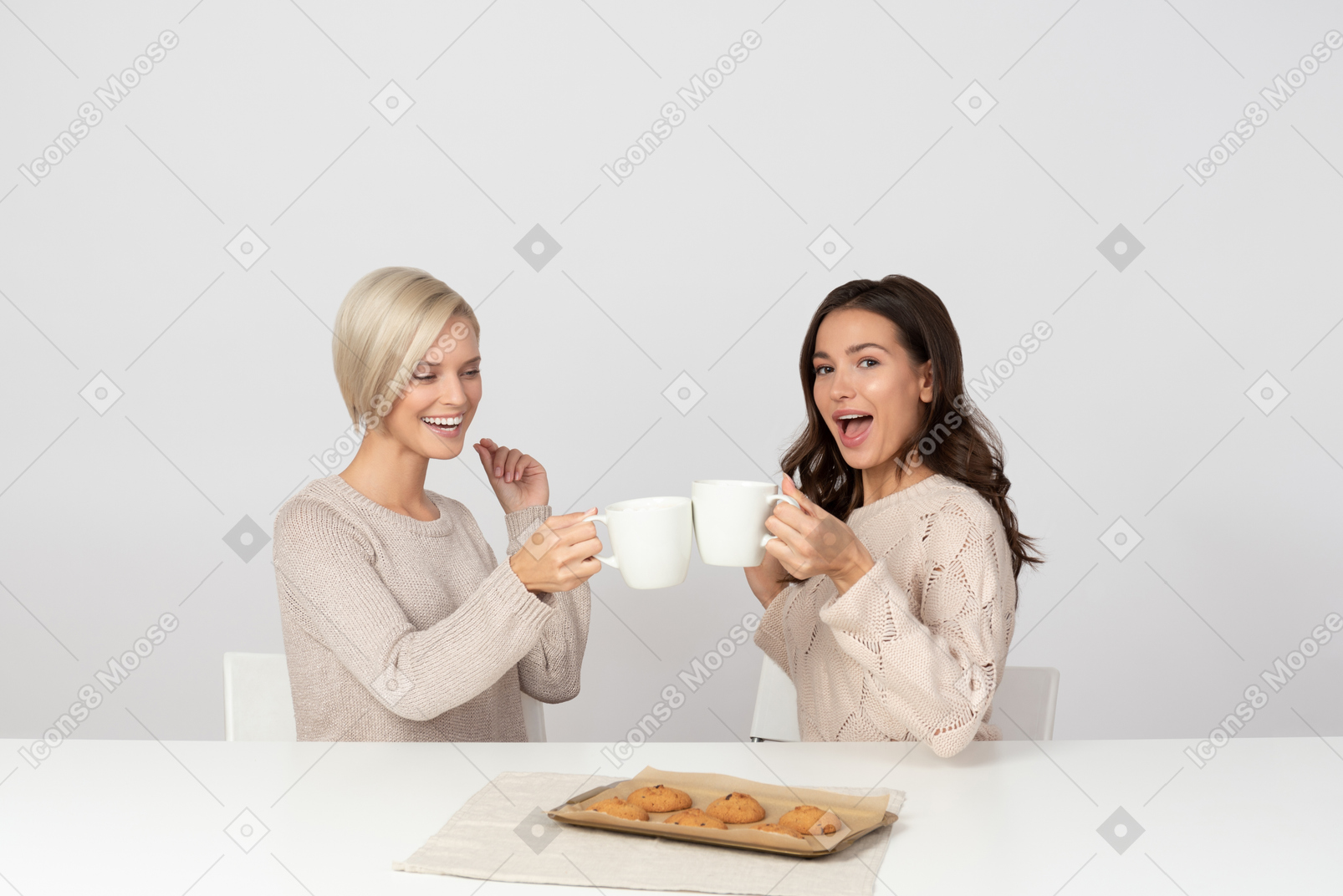 Young women drinking coffee with cookies and laughing