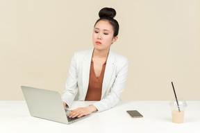 Smiling asian female office worker working on laptop